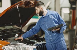 Mechanic performing preventative maintenance under the hood